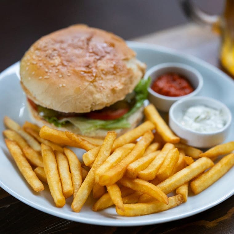 A burger and fries shot on a phone - flat lighting on a plain white plate